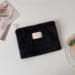 Detail of black plush storage bag with pink bow and soft texture on minimalist background