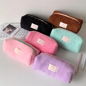 Close-up of assorted plush faux fur pencil cases with zipper and woven brand labels