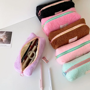 Detail view of colorful teddy fleece pencil cases with zipper and woven brand labels