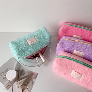 Detailed view of mint green plush pencil case showing red lining and makeup storage