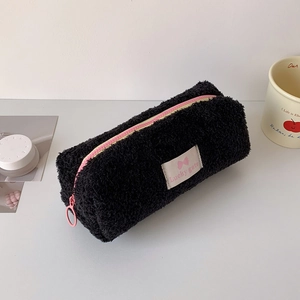 Detail of black plush pencil case featuring pink zipper and Lucky gate logo label