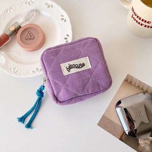 Detail of a purple gingham quilted pouch featuring hisocute label and cotton rope zipper