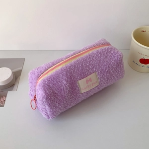 Detail of purple plush pencil case featuring a zipper closure and lucky gate logo patch