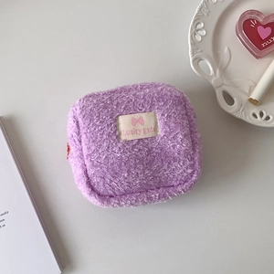 Détail de la pochette en peluche violette avec texture douce et étiquette tissée élégante