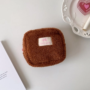 Détail de la petite pochette carrée en peluche marron avec étiquette en tissu