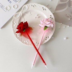 Detalle de bolígrafos de rosa roja y rosa con plumas en plato de cerámica con perlas