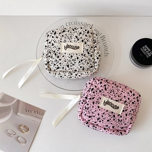 Quilted ink splatter lipstick pouch in beige and pink canvas with long ribbon zippers