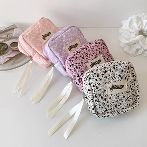Detailed view of four colorful quilted square pouches with ink-splash textures and long pullers