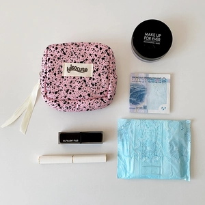 Pink quilted ink splatter cosmetic bag with square design and white zipper closure