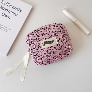Close-up of pink quilted makeup bag with black splatters and white ribbon puller