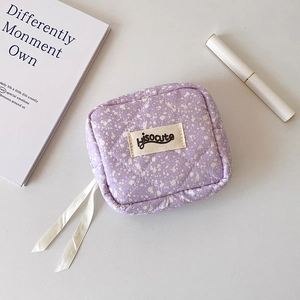 Detail of purple quilted makeup pouch with ink splash pattern and velvet ribbon zipper