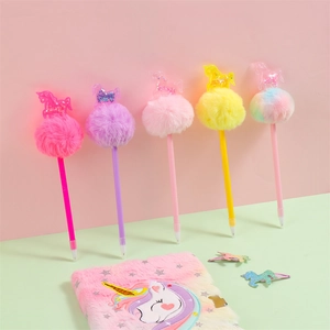 Close-up of colorful unicorn pom pom pens with glitter sequins and plush notebook