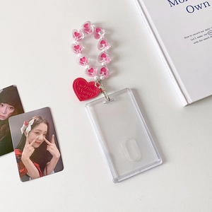 Detail of clear card holder with pink heart beads and red heart pendant on desk