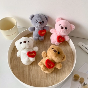 Close-up of four colored plush bears with embroidered love hearts on a wooden tray