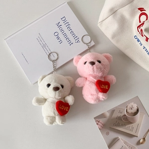Close-up of plush white and pink bears with red love hearts and metal keychains