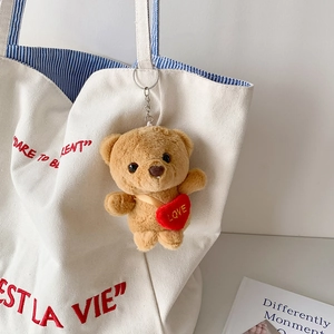 Cute brown plush bear keychain with red LOVE heart on a white canvas bag