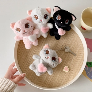 Cute plush cat keychains in four colors with heart pendants on a round wooden tray