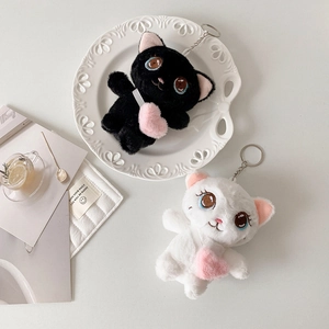 Detail of plush cat keychains in black and white with heart bags and metal clips