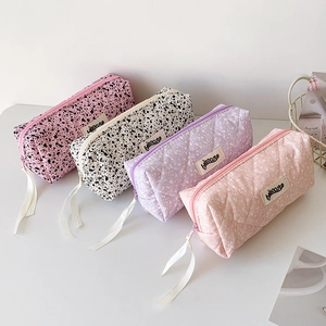 Minimalist ink-splash style pencil cases in four pastel colors on a clean desktop