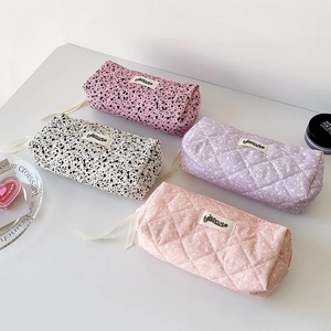 Macro detail of four fabric stationery pouches with ink-splash patterns and ribbon zippers
