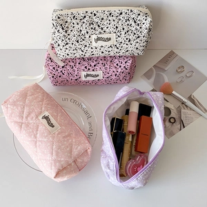Detail of quilted cosmetic pouches in floral and ink patterns showing large storage capacity