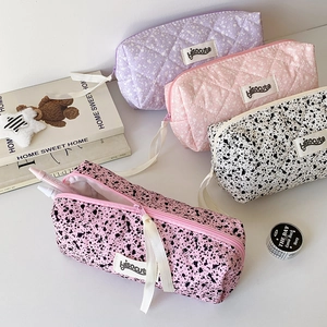 Detail of four quilted zipper pouches with long white ribbons and minimalist ink splash pattern