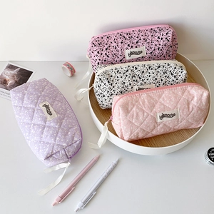 Close-up of quilted pencil cases with ink-splash patterns and ribbon zipper pulls