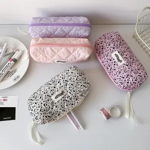 Close-up of quilted fabric pencil cases in assorted colors with ribbon zipper puller