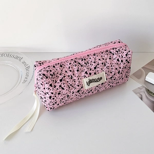 Detailed close-up of pink quilted pencil case with ink splatter pattern and zipper