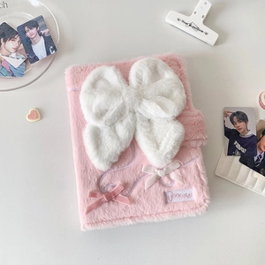 Close-up of pink plush photocard album cover with large white bow and buckle closure