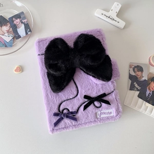 Detailed view of purple plush photo album cover featuring a large black bow and branding