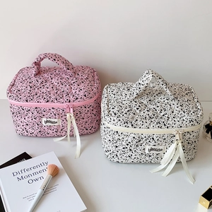 Close-up of quilted cosmetic bags with ink splash pattern and elegant ribbon zippers