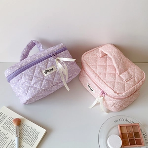 Close-up of quilted cotton cosmetic bag with ink splash print and white ribbon zipper