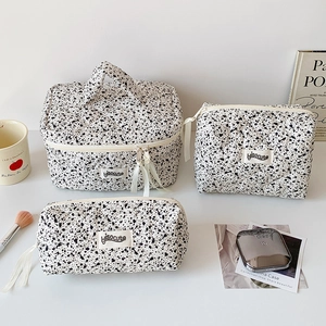 Three-piece quilted cotton cosmetic bag set with black ink-splatter pattern and carry handle