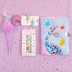 Close-up of sequin mermaid notebook with fluffy ball pen and colorful hair accessories