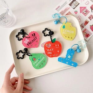 Close-up of five colorful acrylic star and fruit pendants with charms in a white tray
