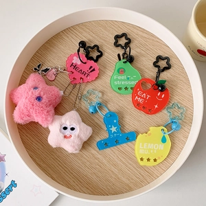 Flat lay of colorful acrylic star and fruit bag charms on a wooden tray with plush stars
