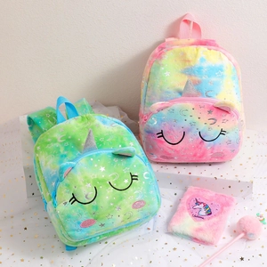 Close-up of tie-dye plush unicorn backpack with matching notebook and furry ball pen