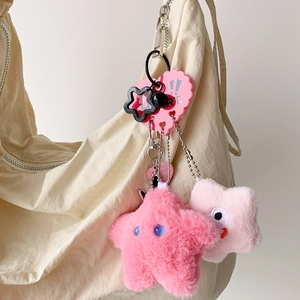 Cute pink plush star charms on a canvas bag featuring metal chains and heart-shaped tags