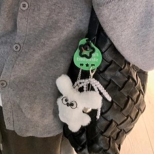 Close-up of a plush white bunny keychain with glasses and a heart-shaped metal pendant