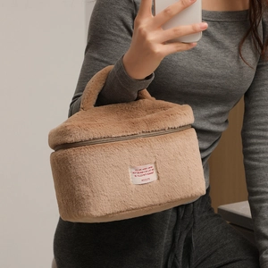 Brown plush makeup bag with soft faux fur texture and top handle for travel storage