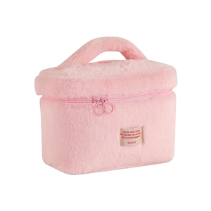 Detail of pink plush makeup bag featuring wide handle, double zipper and cloth label
