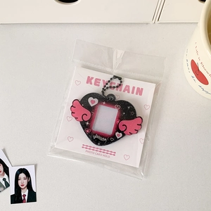 Detail of black glitter acrylic heart photocard holder with pink wings and ball chain