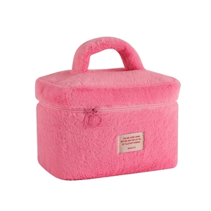Detailed close-up of pink plush cosmetic bag with metal ring zippers and top handle