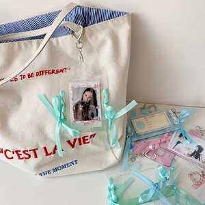 Glinsterende acryl fotokaarthouder met zijden strikken aan een witte canvas tas