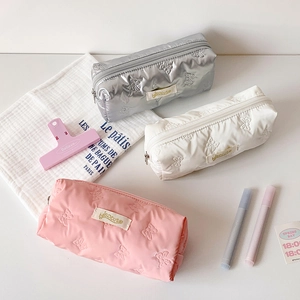 Detailed view of pastel nylon pencil cases with butterfly embossing in silver, white, and pink