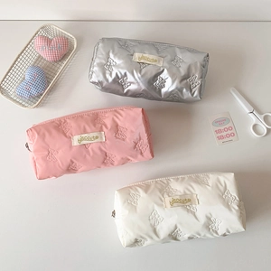 Detail of embossed bow pattern on glossy pastel pencil cases with fabric labels