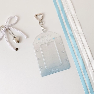 Close-up of clear blue glitter photocard holder with silver heart-shaped metal keychain