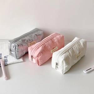 Detail of embossed bow pattern and brand tag on quilted fabric pencil case colors