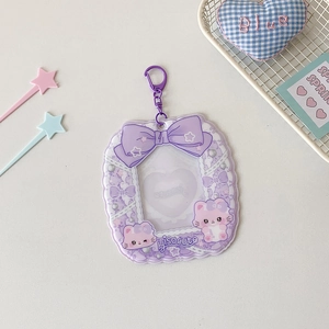 Detail of purple cartoon photocard holder featuring heart window and large bow pendant
